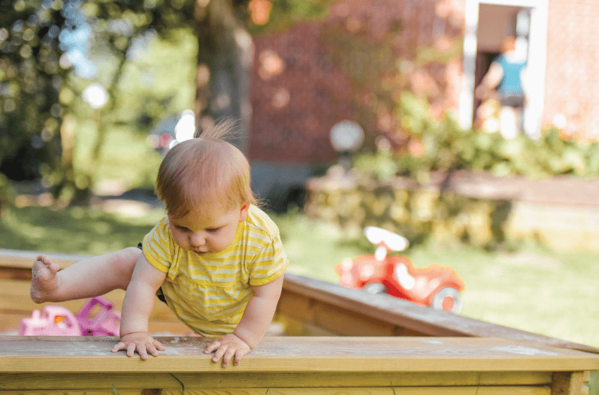 unsupervised toddler climbing out of sandbox.