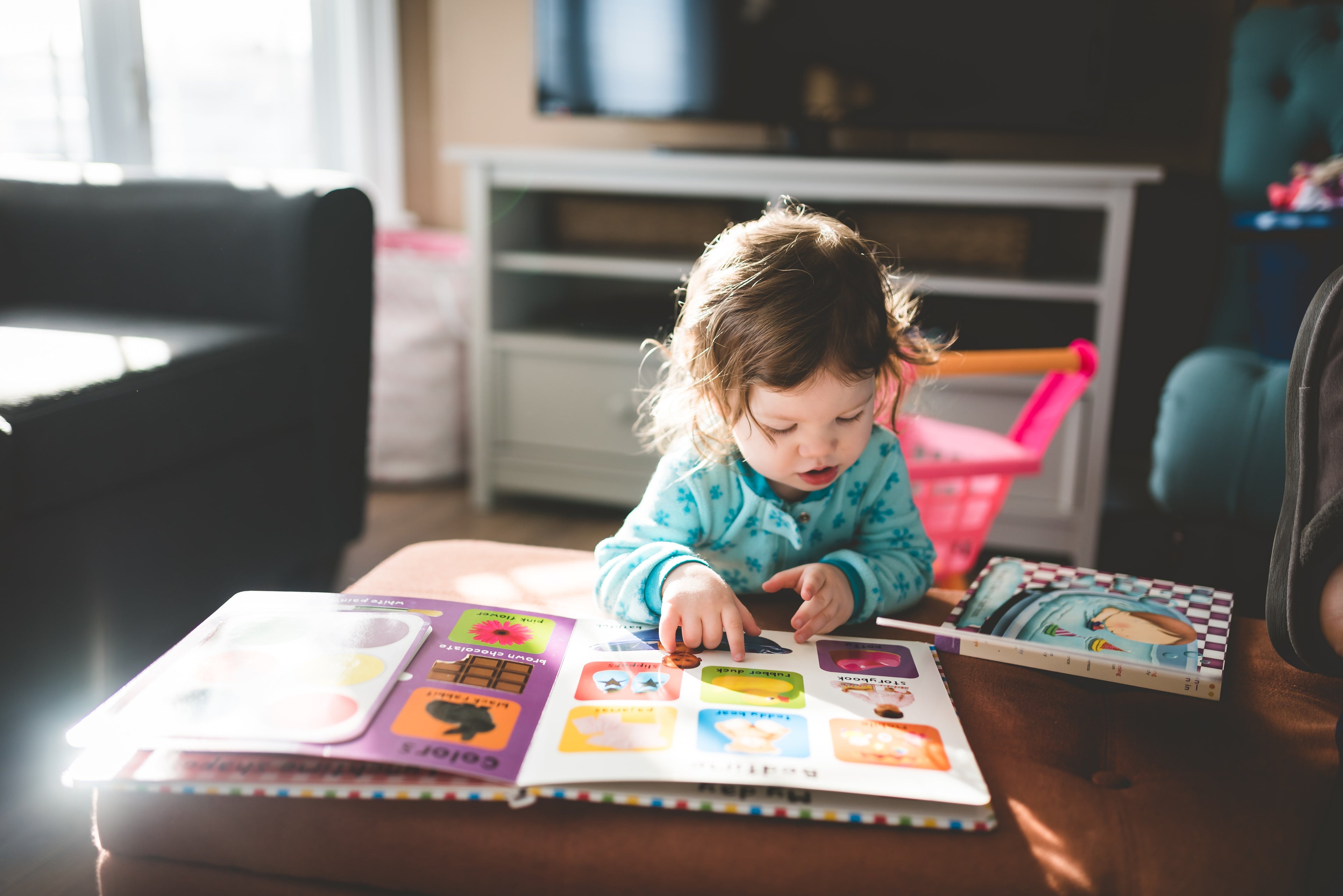 small child reading picture book at table